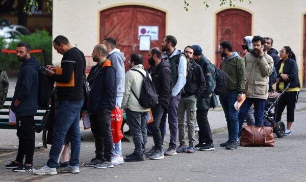 From file: Migrants queue in a waiting area to be escorted to a registration office at the arrival center for asylum seekers in Berlin | Photo: Fabrizio Bensch / Reuters