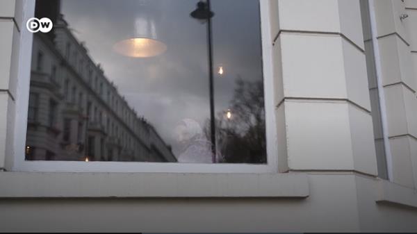 From file: An Afghan woman sits in the window of the hotel which had accommodated Afghan refugees in Lo<em></em>ndon | Photo: Screenshot from DW report / DW / Kate Martyr